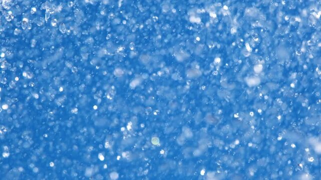 Close-up of sparkling fountain water splashes against clear blue sky. Refreshing droplets create dynamic abstract background representing freshness, summer, energy and motion