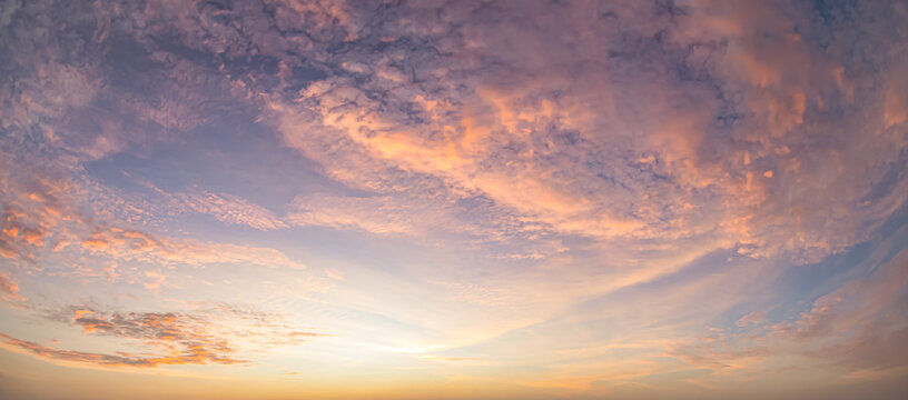 Beautiful sunset sky background with soft pastel pink purple clouds and vibrant golden orange sun glow for panoramic travel mockup design