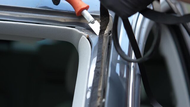 Windshield Adhesive Removal 4k video. Technician uses blade to remove old sealant from vehicle frame. Essential prep for secure glass bonding