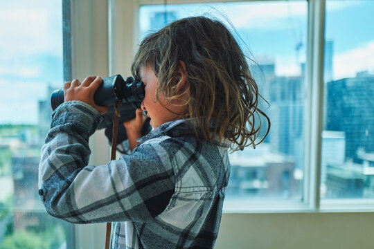 Boy looking through binoculars - side profile with warm backlight