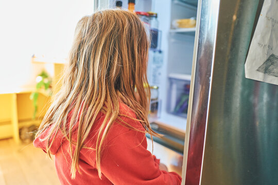 Boy looking into an open fridge in the kitchen