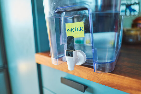 Water filter dispenser on a kitchen counter with handwritten label