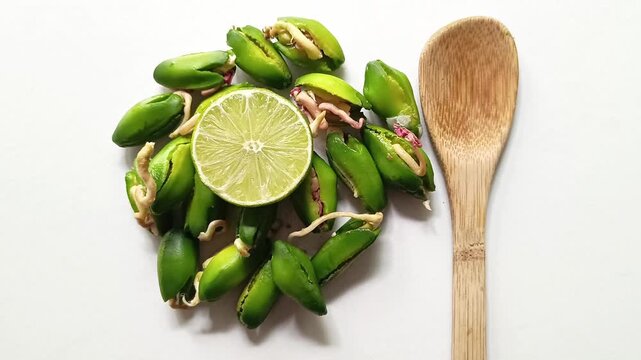 Germinated green paterna seeds of Inga jinicuil arranged with a fresh lime slice and a bamboo spoon for typical dish from Guatemala