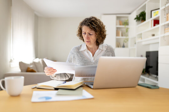 Mature woman stressing over financial paperwork at home