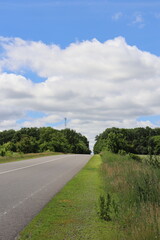 Fototapeta premium Vertical country road beneath dramatic summer clouds