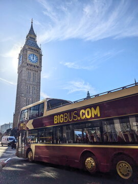 Double-decker tourist bus driving past the historic Elizabeth Tower and Big Ben clock in London