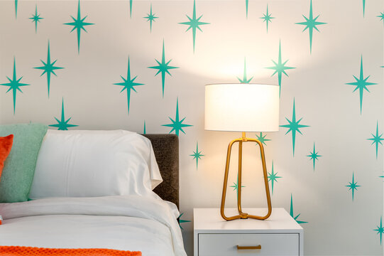 Mid-Century Modern bed with atomic starburst wallpaper and brass lamp