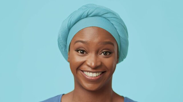 Smiling Black Woman With Headwrap Radiating Happiness, Posing Confidently Against Light Blue Background, Celebrating Natural Beauty And Self-care In A Studio Environment. Beauty Concept.