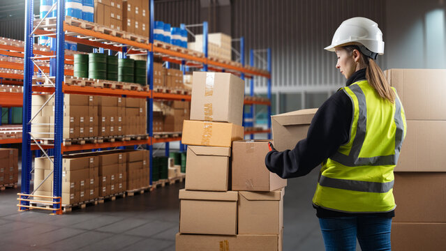 Warehouse operations, female warehouse worker inspecting and organizing cardboard boxes in storage aisle, logistics fulfillment center workflow.
