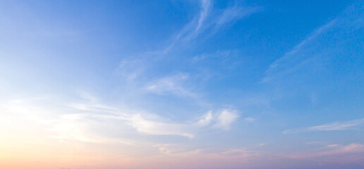 Fototapeta na wymiar Beautiful clear blue sky background with soft pastel orange pink gradient light and wispy clouds for panoramic travel mockup design