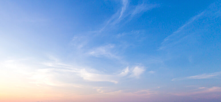 Beautiful clear blue sky background with soft pastel orange pink gradient light and wispy clouds for panoramic travel mockup design