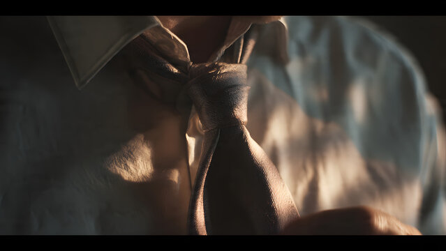 Close Up of Businessman Adjusting Silk Necktie in Dramatic Light