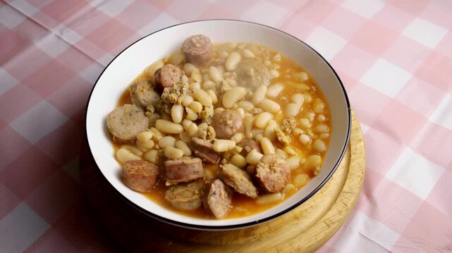 Close up camera zoom of steaming hot white bean stew with sliced sausages