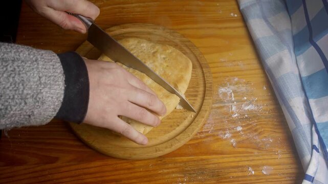Top view of a person cutting fresh steaming homemade stuffed bread with a knife