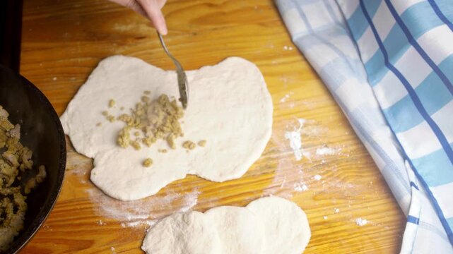 Top view of adding seasoned meat filling onto raw pastry dough