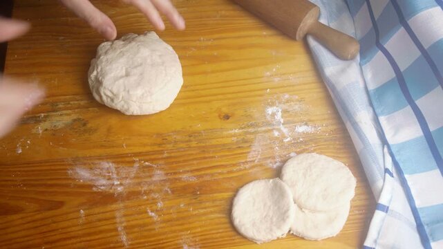 Close up of hands flattening dough with a rolling pin beside fresh sopaipilla circles
