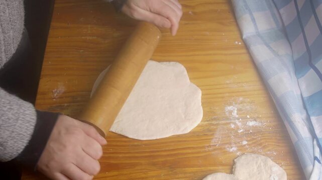 Close up of hands flattening raw pastry dough and molding Chilean sopaipillas