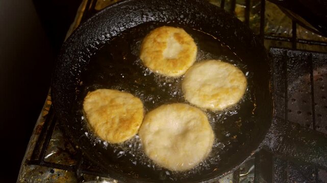 Top view of traditional Chilean sopaipillas deep frying in boiling oil