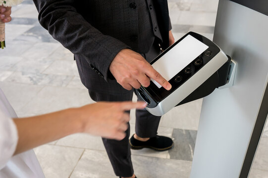 Bride and Groom Taking Queue Number Ticket from Digital Self Service Kiosk at Civil Registry Office Before Wedding Ceremony Modern Public Service and Registration Process