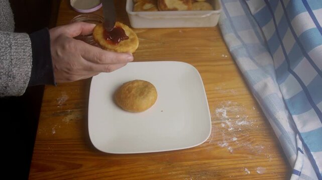 Top view of person spreading sweet strawberry jam onto a fresh Chilean sopaipilla