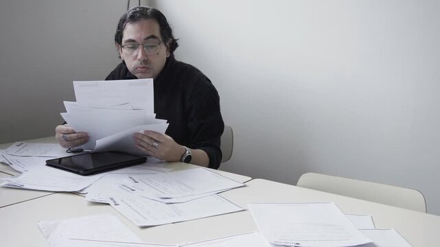 Frustrated and stressed male teacher throwing papers on a desk in anger and disappointment