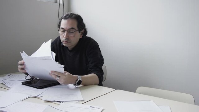 Tired male office worker throwing documents and rubbing eyes in deep exhaustion at desk