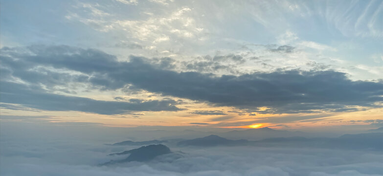 Beautiful sunrise landscape background with dense sea of fog and mountains under dramatic dark grey clouds sky for panoramic travel design