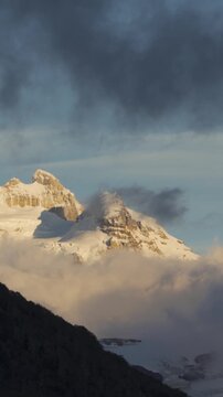 Snow-capped peaks of Cerro Tronador surrounded by clouds at sunset in Bariloche, Argentina