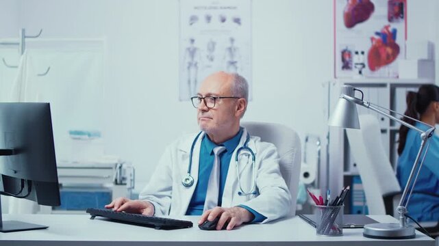 Doctor types at a computer in a private clinic while a nurse checks X rays in the background, linking medical research and consultation work.