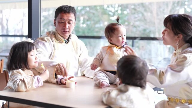 Family shares joyful meal together at table. Parents laugh as children eat with smiles. Warm, bright light enhances happy atmosphere. Perfect for family, parenting, or lifestyle scenes