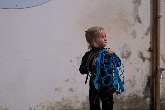 Funny child holding a bunch of tangled surf leashes. 