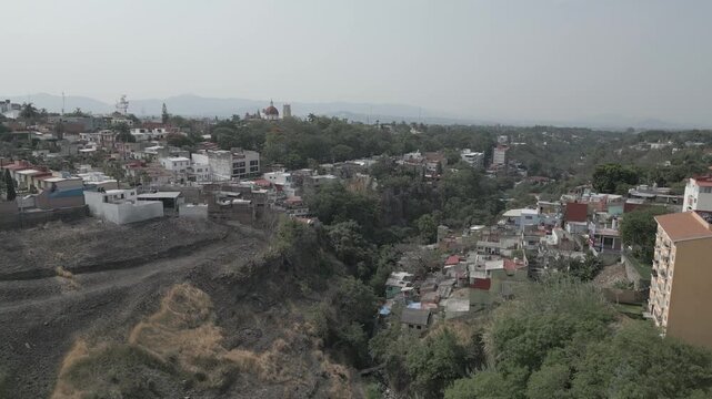 Toma a&eacute;rea de dron con movimiento dolly in sobre la barranca de Amanalco revelando el paisaje urbano y el hist&oacute;rico Jard&iacute;n Borda en Cuernavaca, M&eacute;xico.