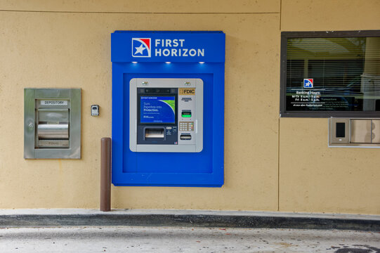 A First Horizon bank ATM mounted in a bright blue kiosk against a beige wall. Editorial Use Only July 11, 2026 St. Petersburg, FL USA showing FDIC signage, card reader, keypad and cash slot; clean ext