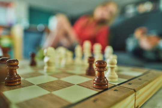 Chess pieces in focus with a child watching from the sofa