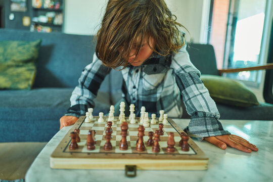Boy concentrating over a chess board at home