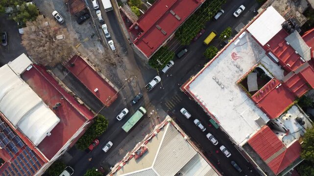 Vista a&eacute;rea cenital del tr&aacute;fico urbano en una intersecci&oacute;n de calles con techos coloridos en Cuernavaca, M&eacute;xico.