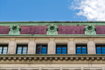 Upper facade of a historic apartment building with a purple mansard roof in Boston, USA  © Baharlou