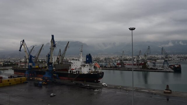 Commercial cargo ships and industrial cranes operate at a busy Turkish seaport beneath dramatic storm clouds. The harbor highlights maritime trade, shipping logistics, port infrastructure, and interna