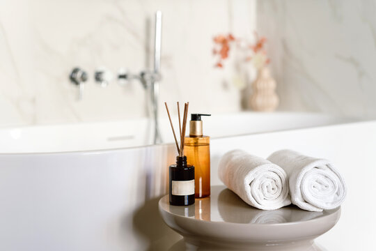 Shower gel and towels on a table near a bathtub in a hotel bathroom setup