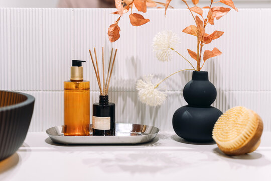 Bathroom counter with soap dispenser, aroma diffuser and flowers
