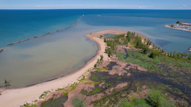 Aerial revealing shot of Presque Isle State Park beach and marina