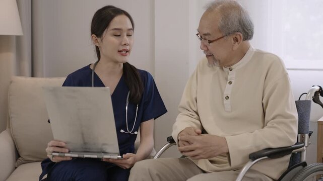 Professional young Asian woman nurse caregiver holding clipboard is talking, explaining, and providing healthcare advice to senior male patient while sitting in wheelchair in special room at hospital.