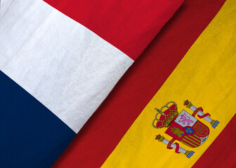 Fototapeta na wymiar High-angle macro shot of the textile national flags of France and Spain overlapping to symbolize sports rivalry or diplomacy.
