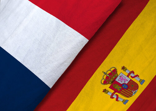 High-angle macro shot of the textile national flags of France and Spain overlapping to symbolize sports rivalry or diplomacy.