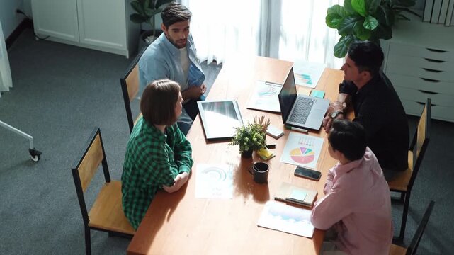 Skilled project manager walking at table while colleague brainstorm idea. Business team working together to plan marketing strategy while looking at data analysis or financial statistic. Convocation.