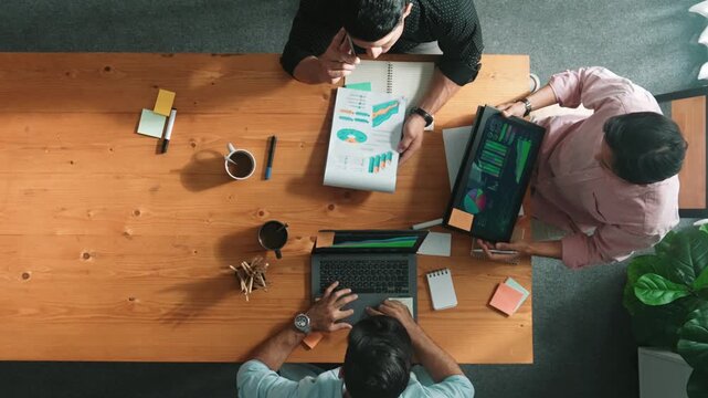 Smart project manager calling phone while diverse team brainstorm idea and looking at financial statistic at tablet at meeting table. Diverse business people planning marketing strategy. Convocation.