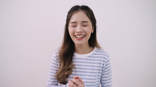 Happy beautiful young Asian woman standing smiling and waving while talking via video camera, webcam, chat by video calling with technology internet app connecting from a smartphone in white studio. 