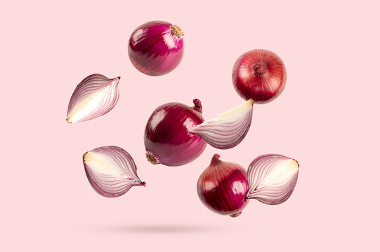 Levitating Red Onion of whole, halved, and sliced on soft pink background.