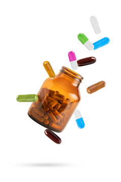 Colorful medical capsules and herbal supplements flying out of an amber glass bottle. Healthcare and pharmacy concept isolated on white background.