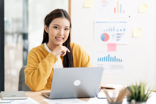 Happy Young Asian Woman Smiling at Camera While Working on Laptop
